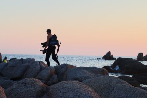A young man with equipment for diving on the seashore at sunset, France