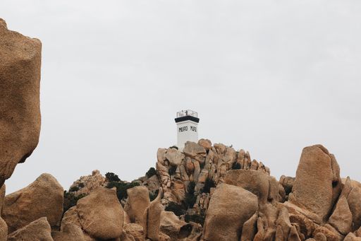 An old lighthouse on rock formations under a cloudy sky on a gloomy day