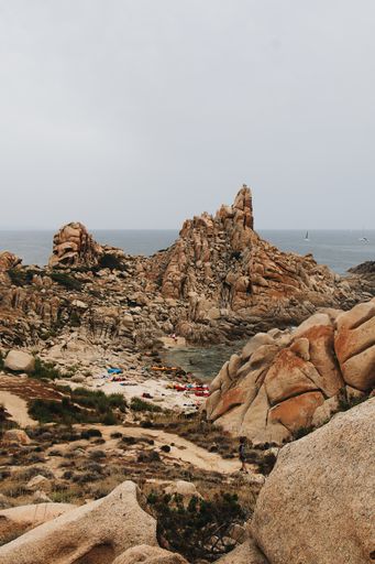 A vertical shot of a rocky shore surrounded by the sea under a cloudy sky