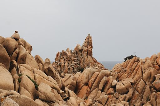 A landscape of a rocky shore surrounded by the sea under a cloudy sky