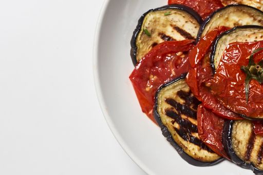 A closeup shot of tomatoes with eggplant in bowl isolated on white background