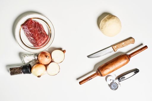 An overhead shot of fresh raw meat with ingredients isolated on white background