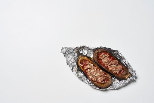 A top view of grilled eggplants with meat and tomatoes in the foi