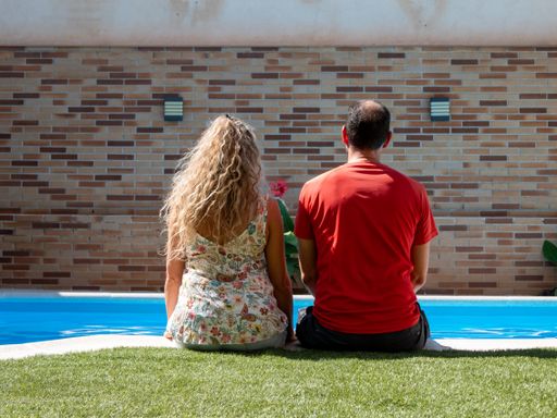 A back view of a romantic couple sitting together near a pool