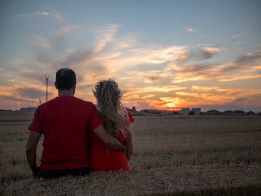 A back view of a romantic young couple looking at the sunset on a beach