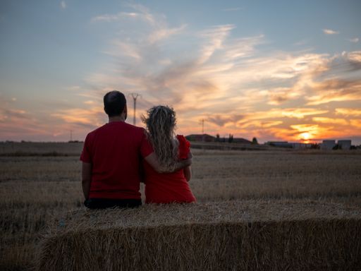 A back view of a romantic young couple looking at the sunset on a beach