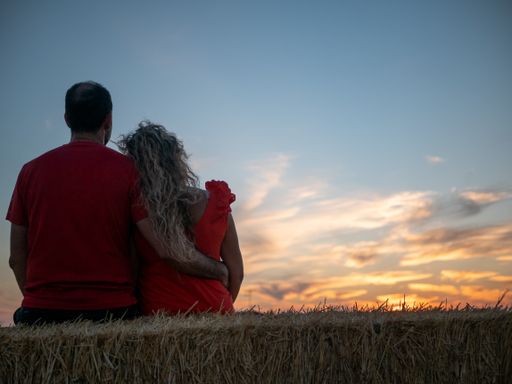 A back view of a romantic young couple looking at the sunset on a beach