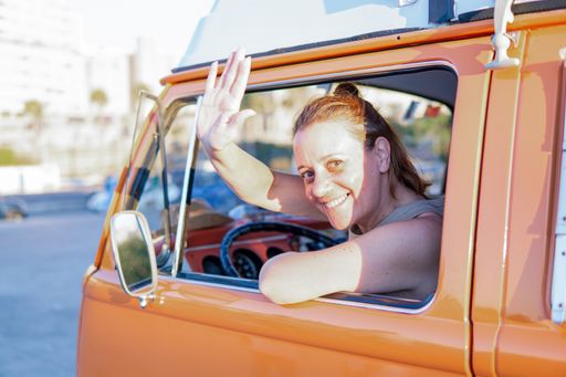 Side view of a Portrait of a beautiful young Caucasian woman smiling and driving a vintage van.