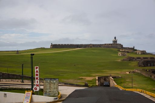 View of El Morro Fort in San Juan, Puerto Rico with parking signs in the foreground under a cloudy sky.