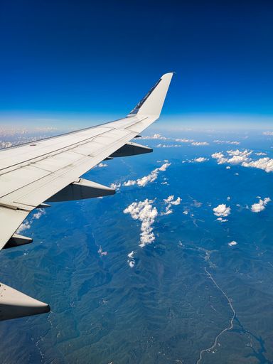 A vertical shot of an airplane wing with the highlands seen in the view