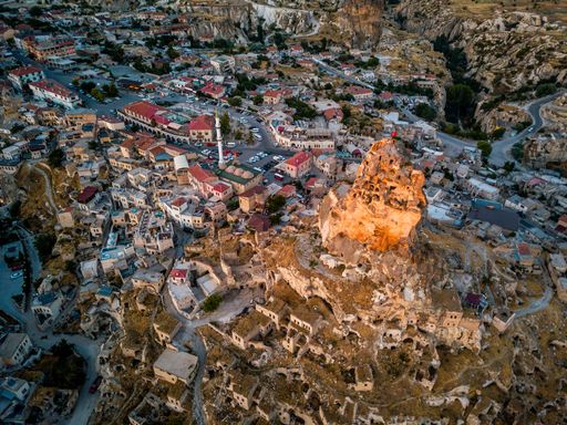 An aerial shot of the Uchisar Castle surrounded by buildings and rock formations in Cappadocia, Turkey