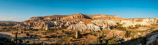 A panoramic shot of a valley surrounded by old rock formations on a sunny day in Cappadocia, Turkey