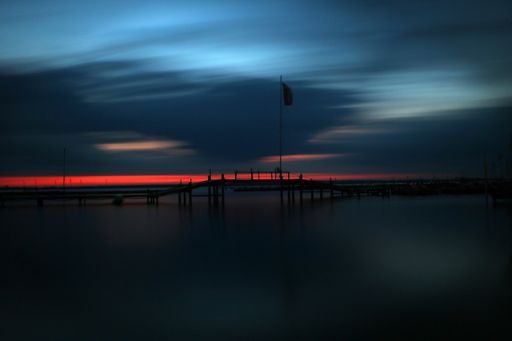 A dark summer evening at a dock with a bright blue sky above the pier