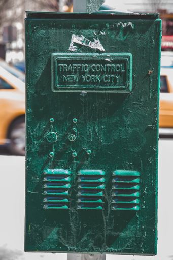 A vertical shot of a green metal cabinet with a traffic control sign in New York City