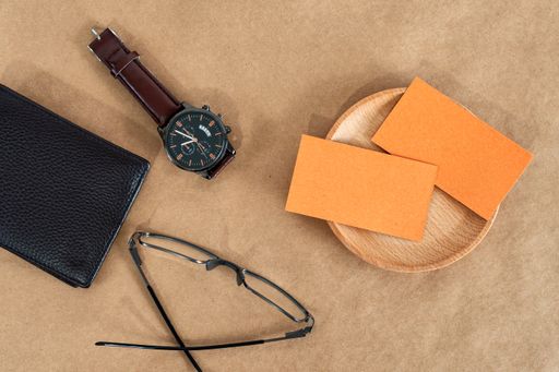 A top view of gentlemen's accessories on the wooden background. Watch, money pockets, eyeglasses, and business cards