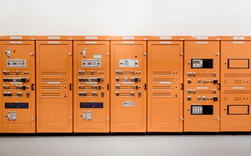 Bright orange industrial control panels with various switches and displays in a modern facility.