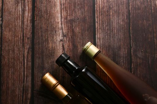 A top-view of oil and wine bottles on a rustic wooden table with copy space