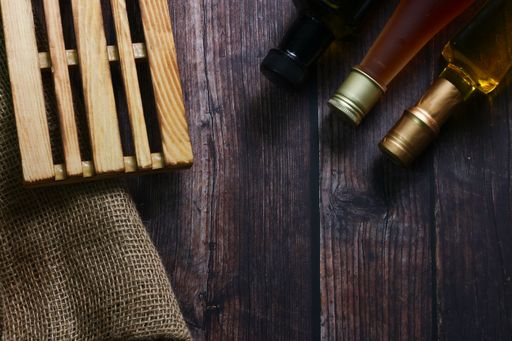 A top-view of oil and wine bottles on a rustic wooden table with copy space