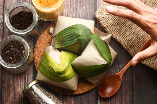 A top view of coconut flavored rice wrapped in banana leaves and various seasonings