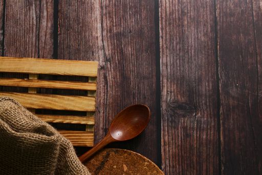 A top view of a spoon, board, and a piece of cloth on a wooden table