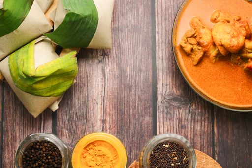 A top view of coconut flavored rice wrapped in banana leaves and various seasonings on a table