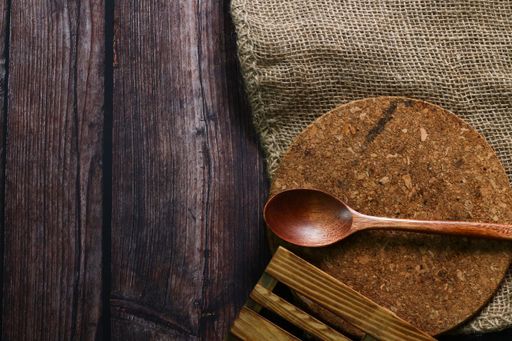A top view of a spoon, board, and a piece of cloth on a wooden table