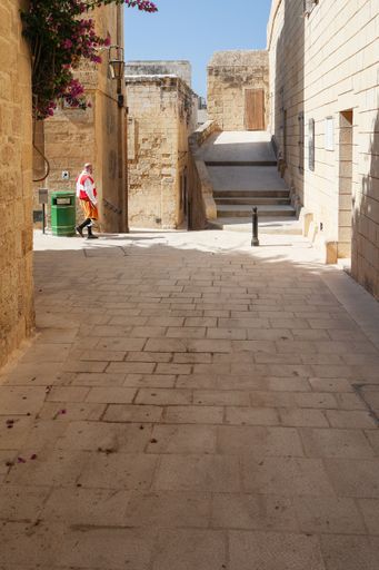 Throwback to a past century. Ambience of the rule of the Knights of Saint John as man dressed as a knight walks in a street of Mdina, Malta
