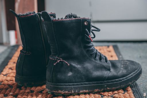 A closeup shot of a pair of black lace-up boots on a rug
