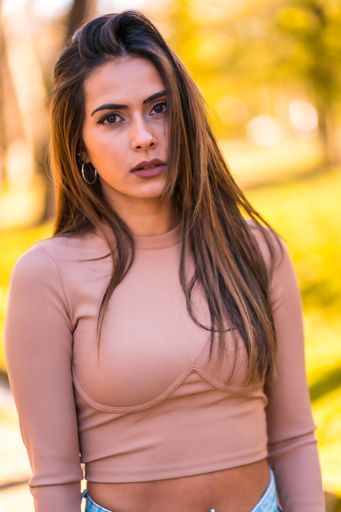 A vertical shot of a brunette model in a pink sweater and jeans walking in autumn