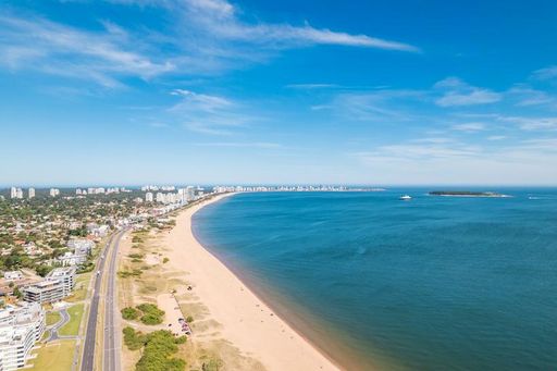 Aerial view of Punta del Este coastline with sandy beach, road, and city skyline under a clear blue sky in Uruguay