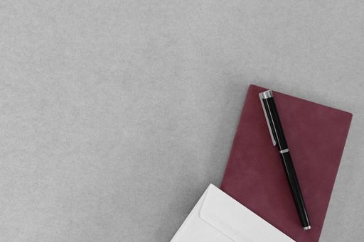 A male style business background with a notebook, pen, and envelope on a gray surface; a copy space on the left