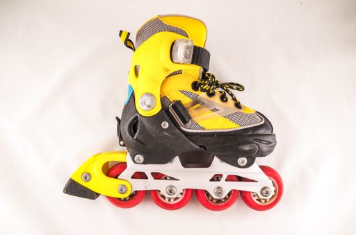 A closeup shot of a small yellow roller skate on a white background