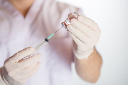 A health worker drawing vaccine in vial into syringe for COVID-19, measles, flu shots