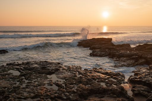 Picturesque view of the sun setting down over rocky shore of Atlantic ocean in Portugal
