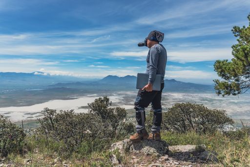 A Hispanic man taking a shot of Laguna Alchichica standing on a stone in Puebla, Mexico
