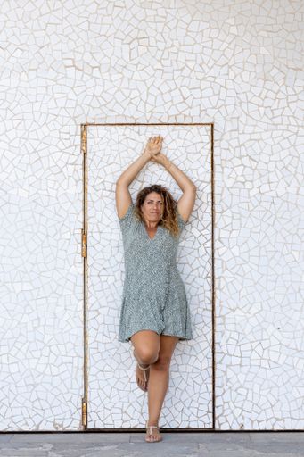 A vertical shot of a Spanish female posing in front of the door