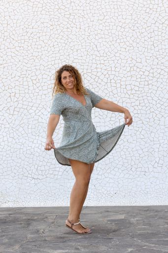 A vertical shot of a Spanish female posing  in front of a white wall