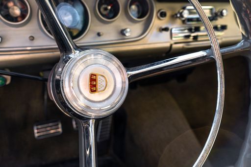 A closeup shot of the wheel and dashboard on an old vintage car