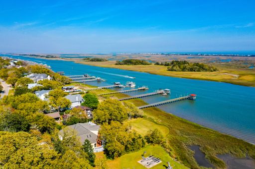 An aerial shot of a lake in the middle of grassy fields with buildings at the Atlantic Coast