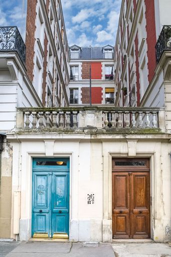 Paris, two ancient wooden doors, colorful facade with a balcony in the 11e arrondissement