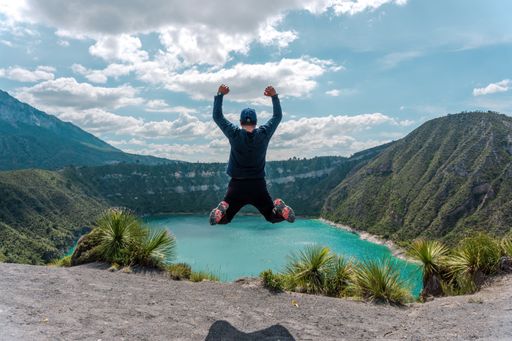 A Hispanic man jumping and celebrating his achievement near Laguna De San Luis Atexcac in Mexico