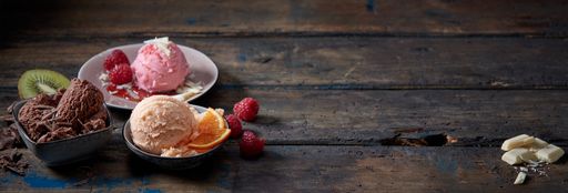 A high angle of scoops of tasty various ice cream on plates placed with fruits and berries on wooden table