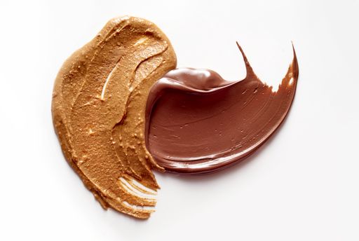 A closeup of delicious peanut butter and chocolate paste spread on white background