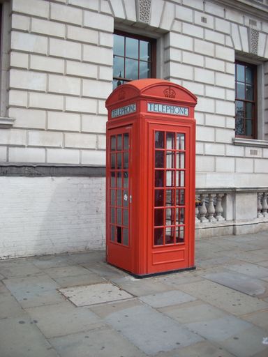 A vertical shot of a red telephone booth in London, UK
