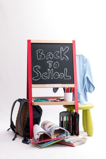 A back to school background - chalkboard, backpack and school items isolated on white background