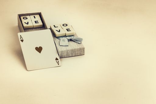 A Valentine's day gift box with blue bow with the phrase give love and a playing card