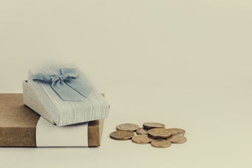 A closeup of coins on the table near small gift boxes against a white background under the lights