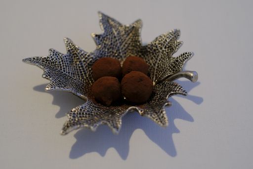 A closeup shot of a chocolate called Triumph in the metal plate which has a leaf shape