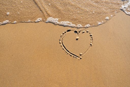 A top view of the heart shape drawn on the sand of the beach in summer