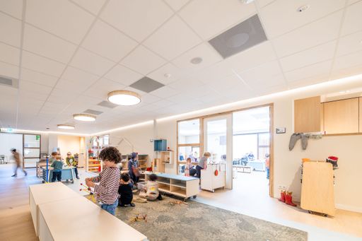 A bright, spacious kindergarten classroom with children playing and engaging in activities, featuring modern furniture and natural lighting.